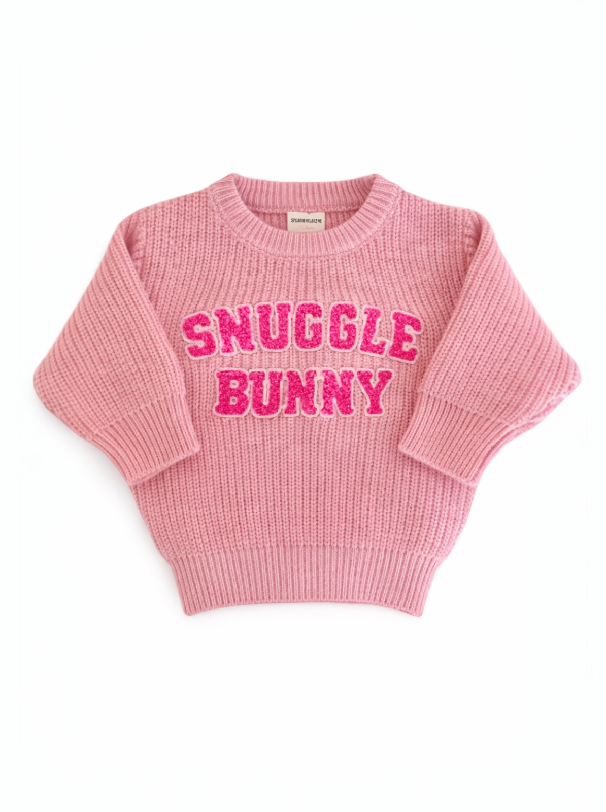 Pink sweater with "SNUGGLE BUNNY" in bold, glittery letters on the front, featuring a cozy knit design.