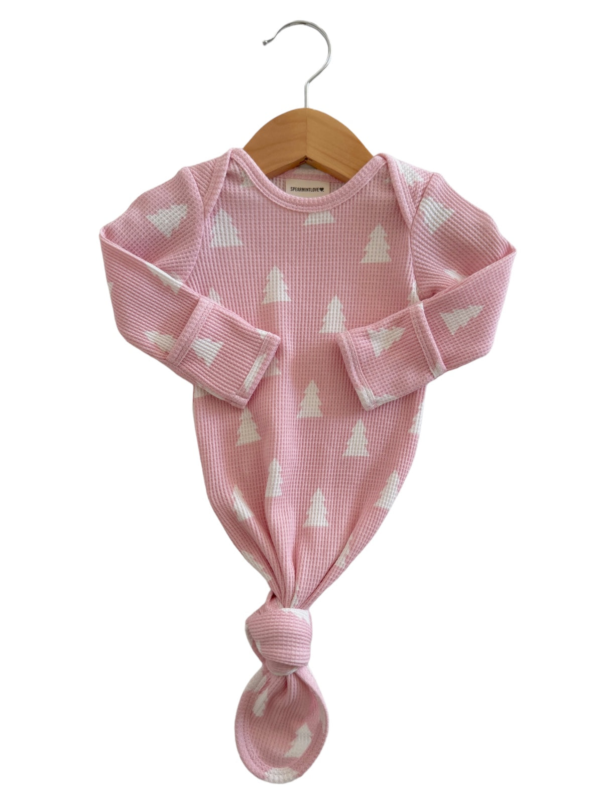 Pink baby gown with white triangle pattern, hanging on a wooden hanger. Ideal for infant wear.