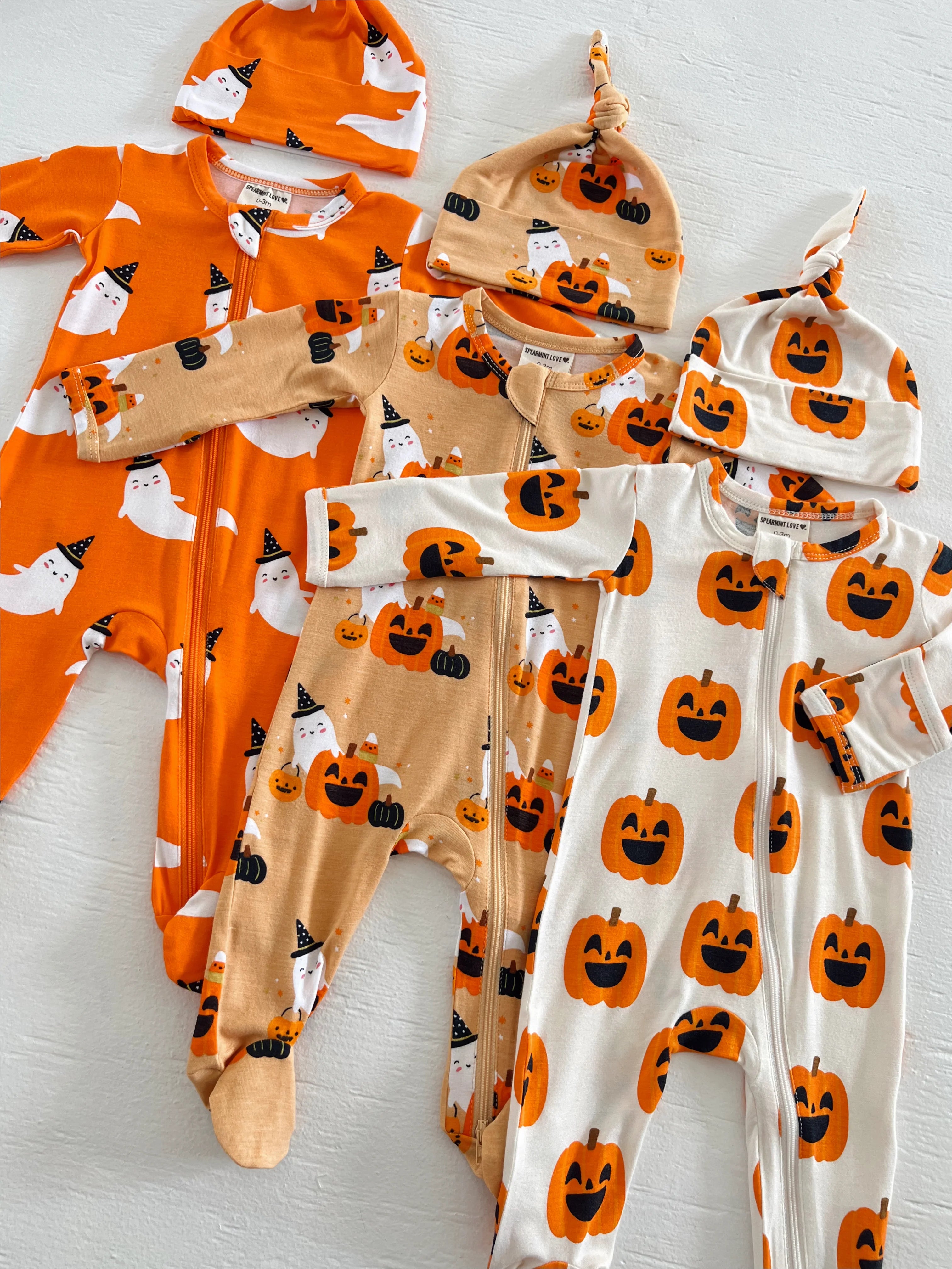 Colorful baby Halloween outfits featuring ghost and pumpkin patterns on onesies and hats.