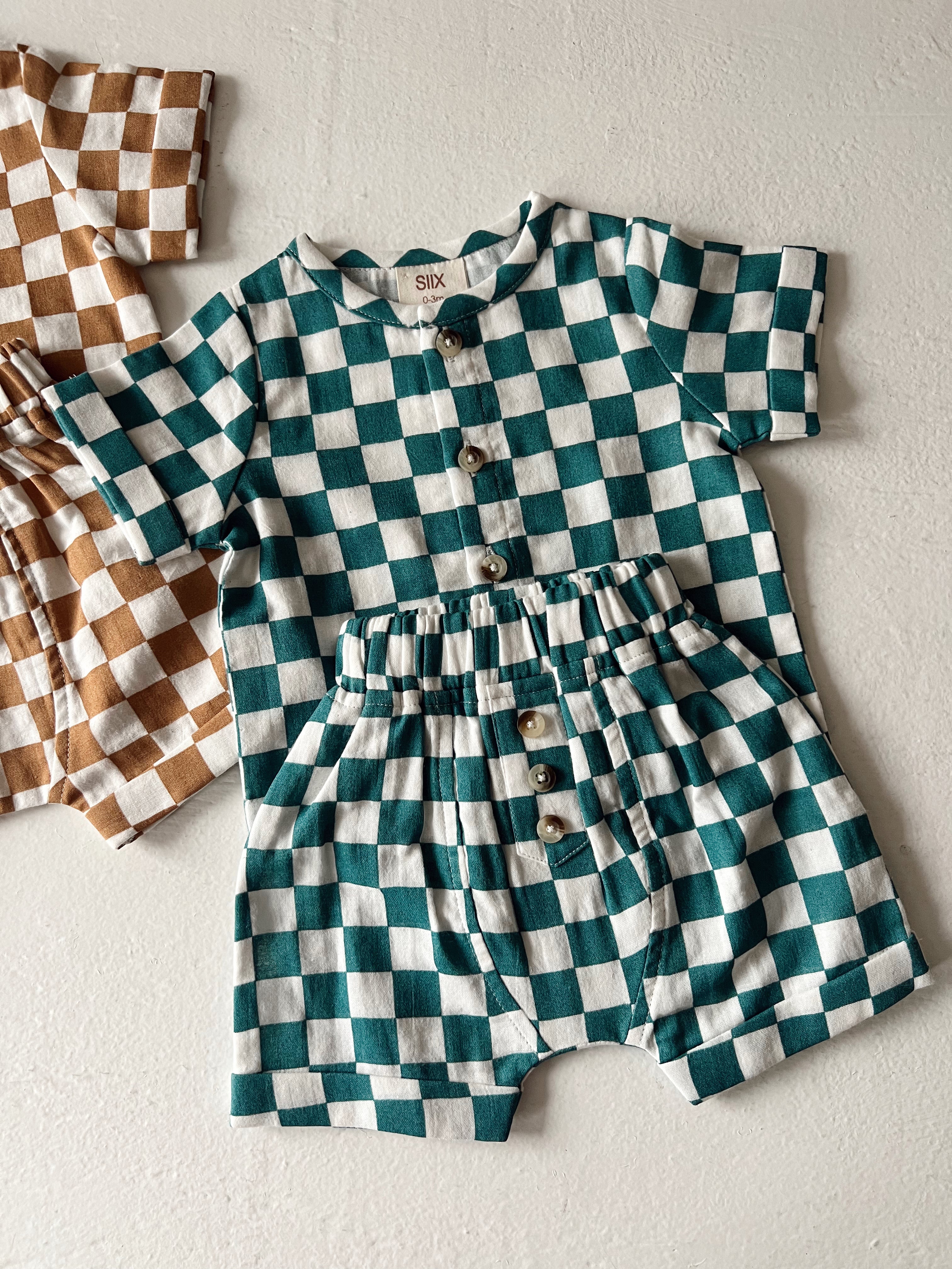 Teal and white checkered toddler outfit with buttons and matching shorts on a light background.