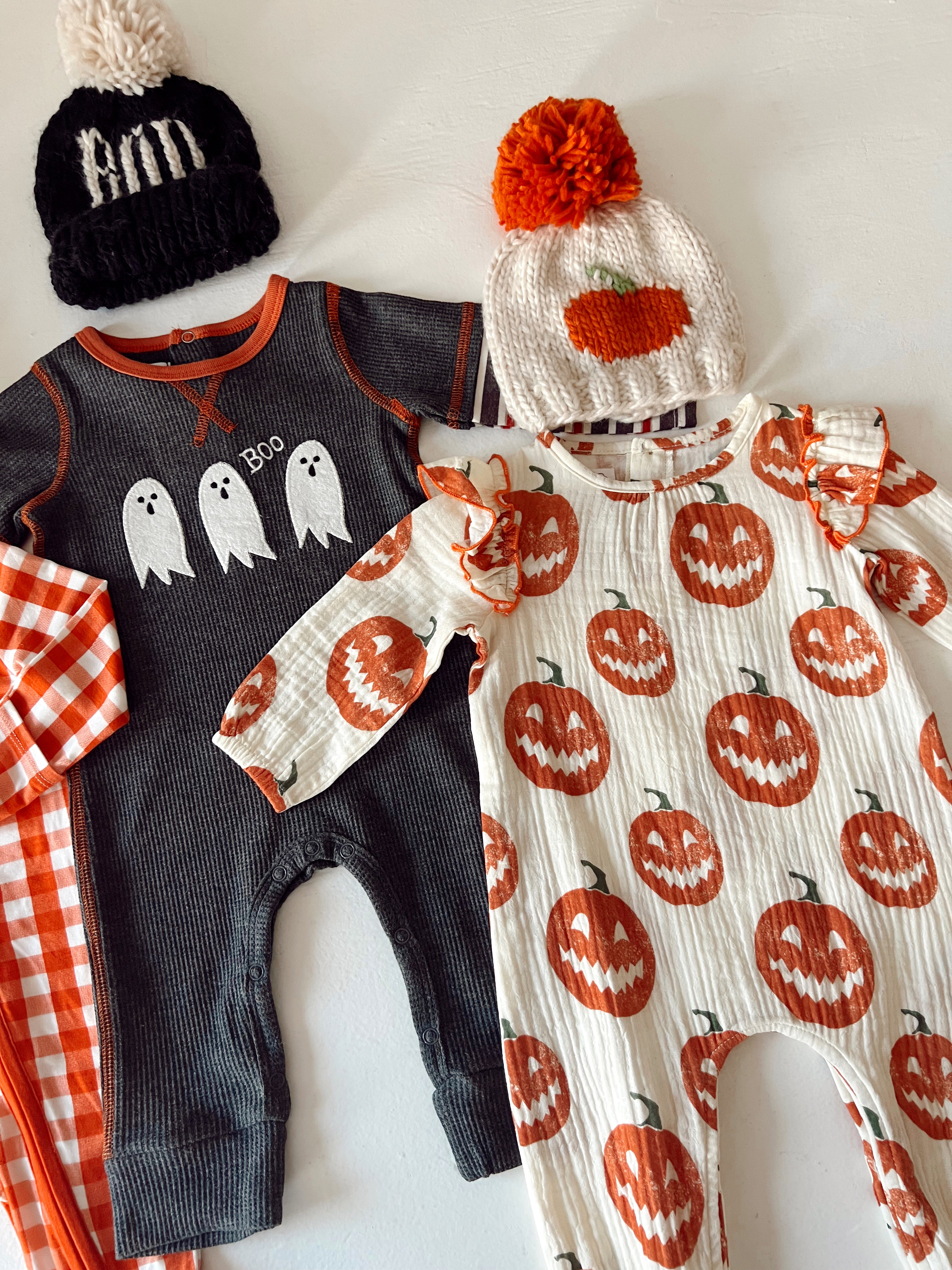 Halloween-themed baby outfits: a ghost-printed onesie, pumpkin-patterned romper, and cozy hats.