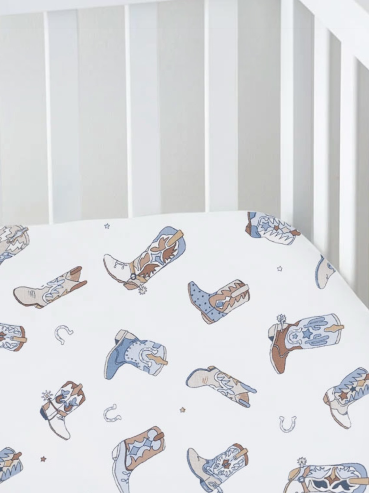 Cowboy boot patterned crib sheet on a white background. Ideal for nursery décor.