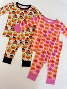 Two sets of kids' pajamas featuring colorful pumpkin prints on white and pink backgrounds. Cozy and festive fall attire.