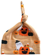 Halloween-themed baby hat featuring smiling pumpkins, a ghost, and candy corn on a light orange background.