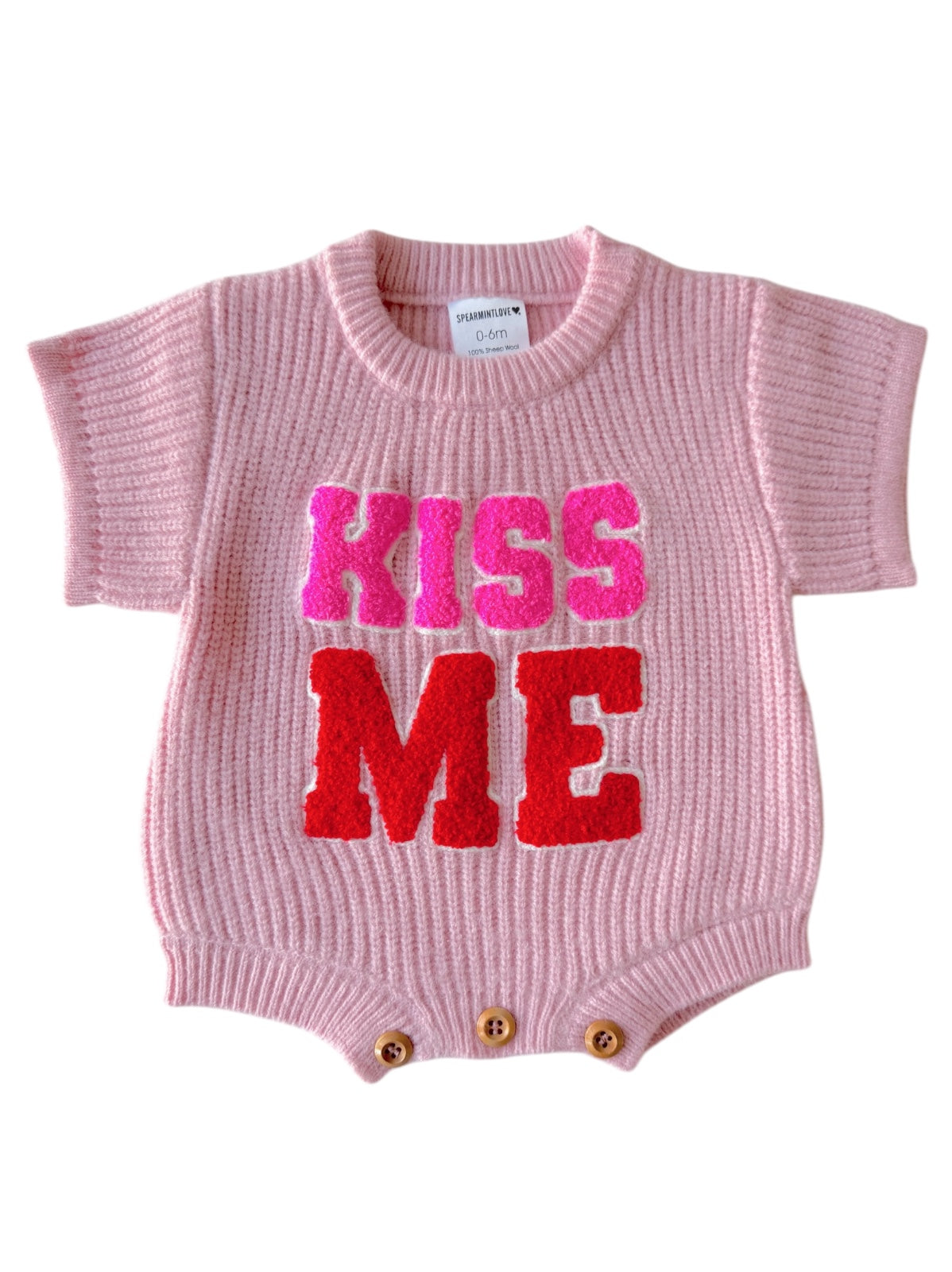 Pink baby romper with "KISS ME" in bold, colorful letters at the front. Short sleeves and button closure at the bottom.