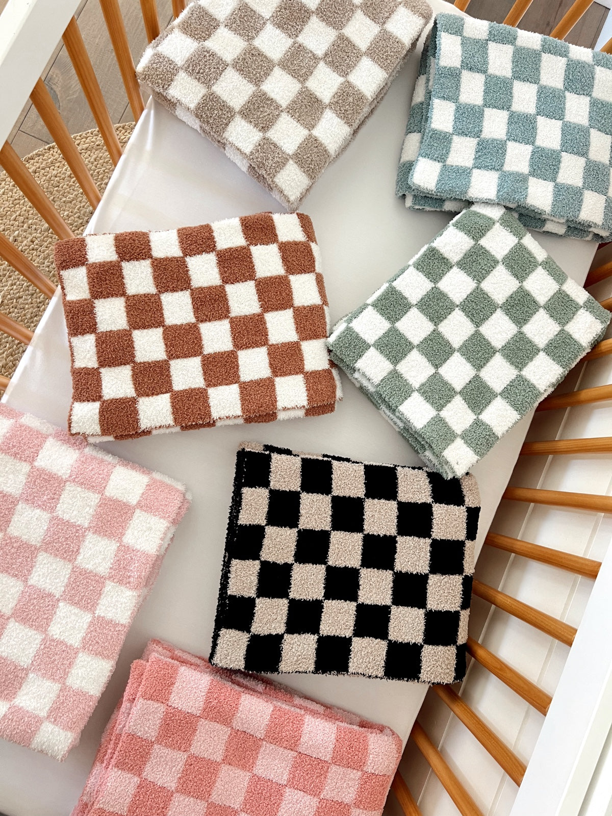 Colorful checkered towels arranged in a crib, featuring various pastel and neutral tones.