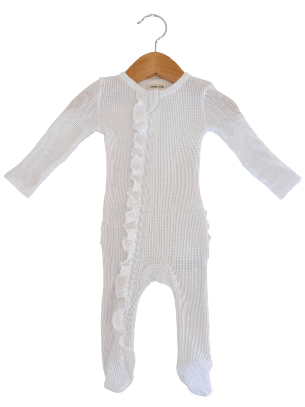 White baby onesie with long sleeves and ruffle detail, hanging on a wooden hanger.