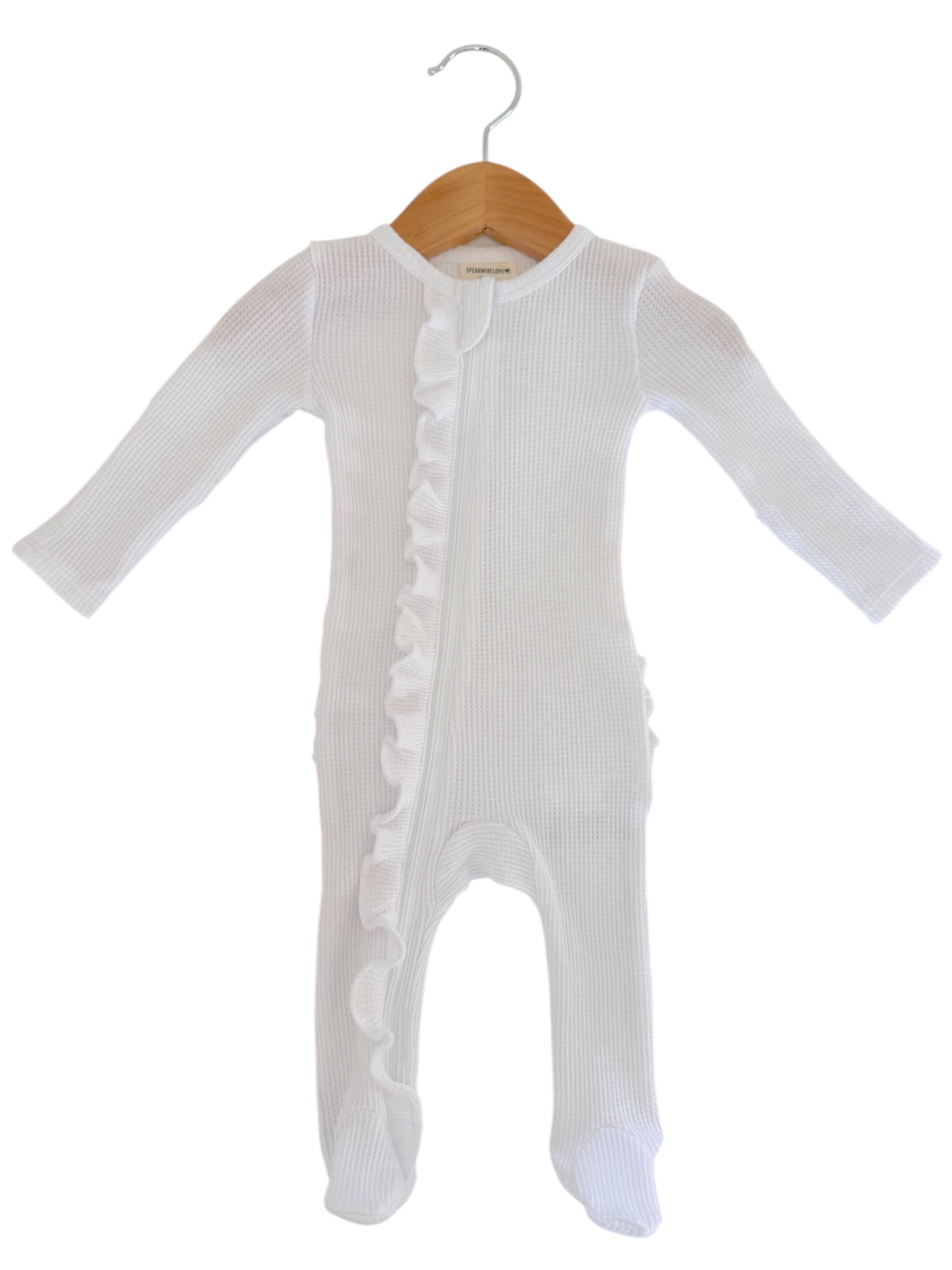 White baby onesie with long sleeves and ruffle detail, hanging on a wooden hanger.
