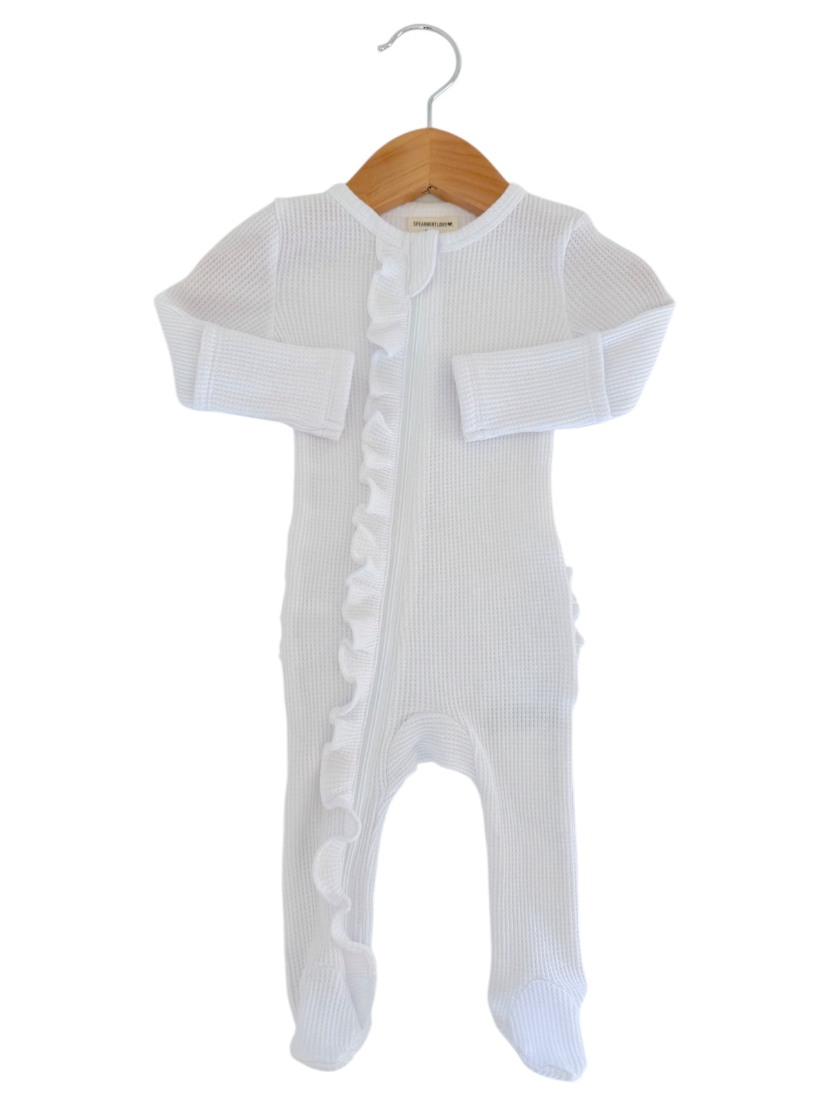 White baby onesie with ruffle detailing, hanging on a wooden hanger against a white background.