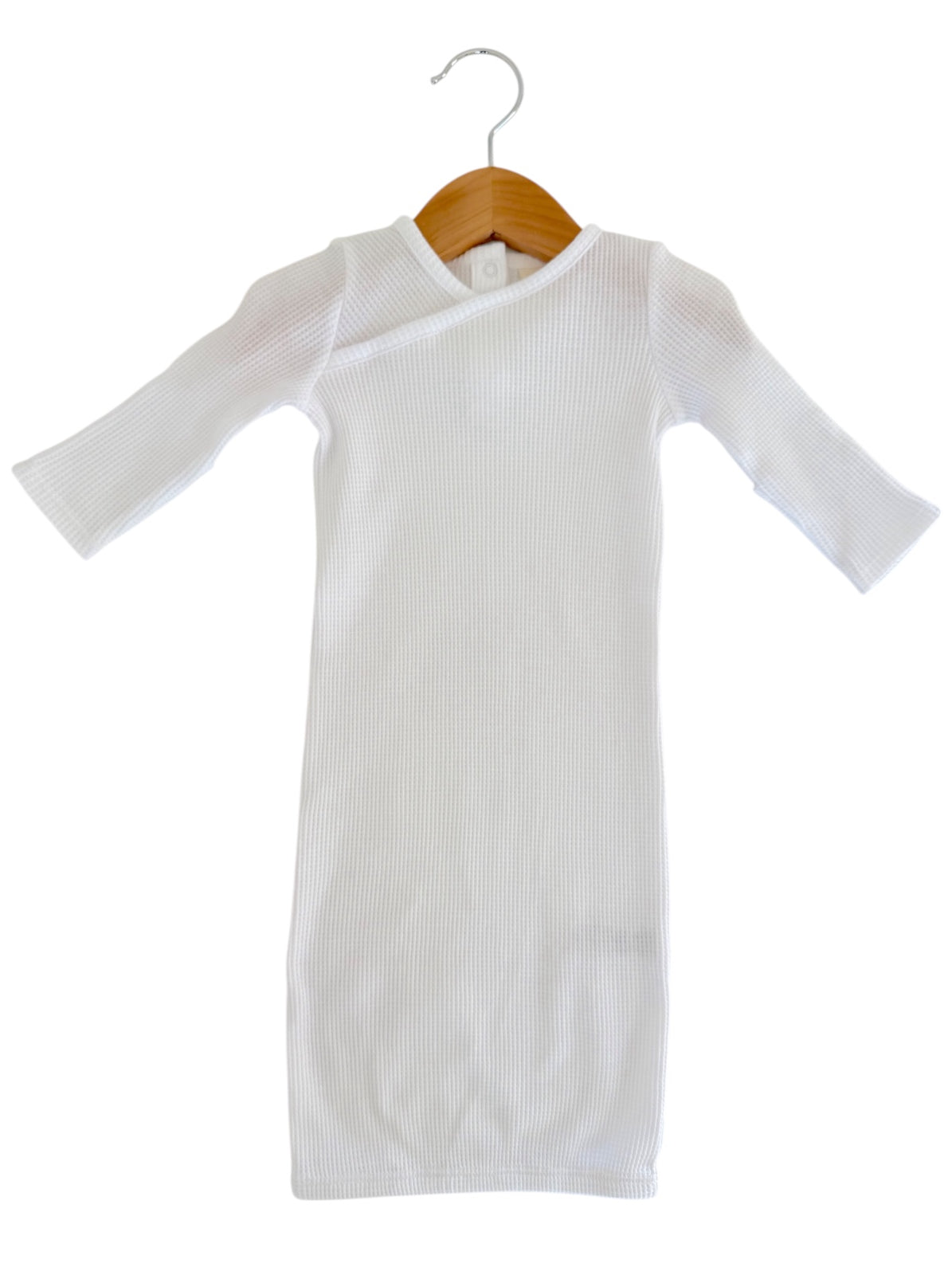 White ribbed long-sleeve dress displayed on a wooden hanger against a white background.