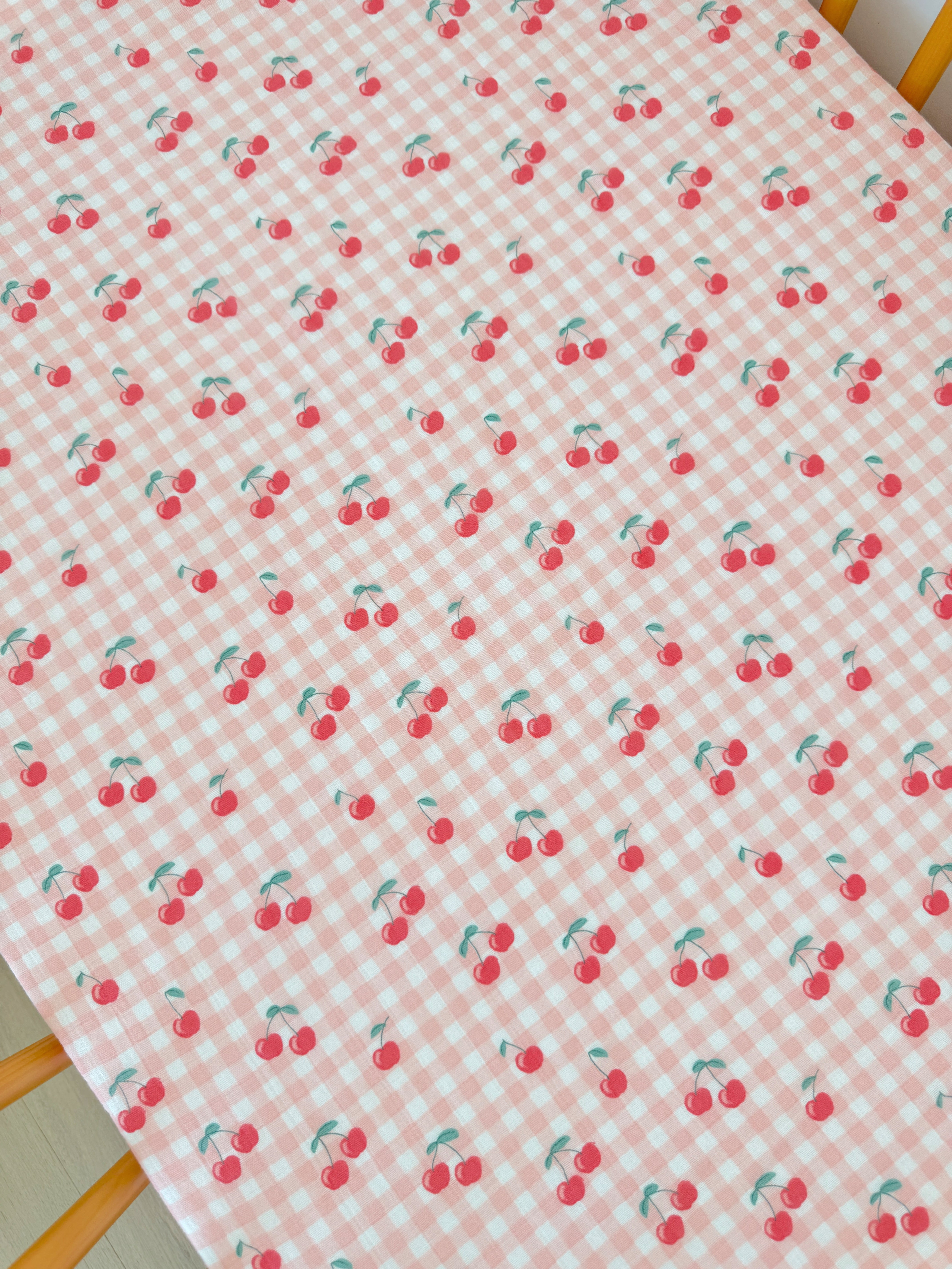 Red cherries on a pink and white checked tablecloth pattern.