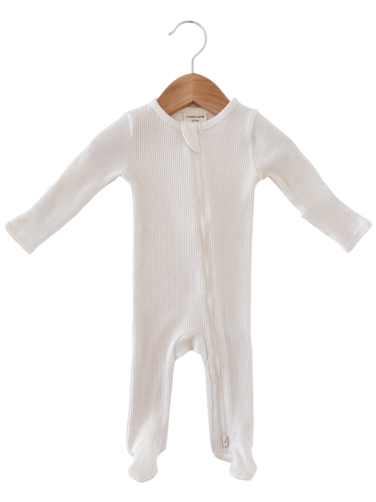 White baby onesie hanging on a wooden hanger, featuring a zipper and ribbed texture.