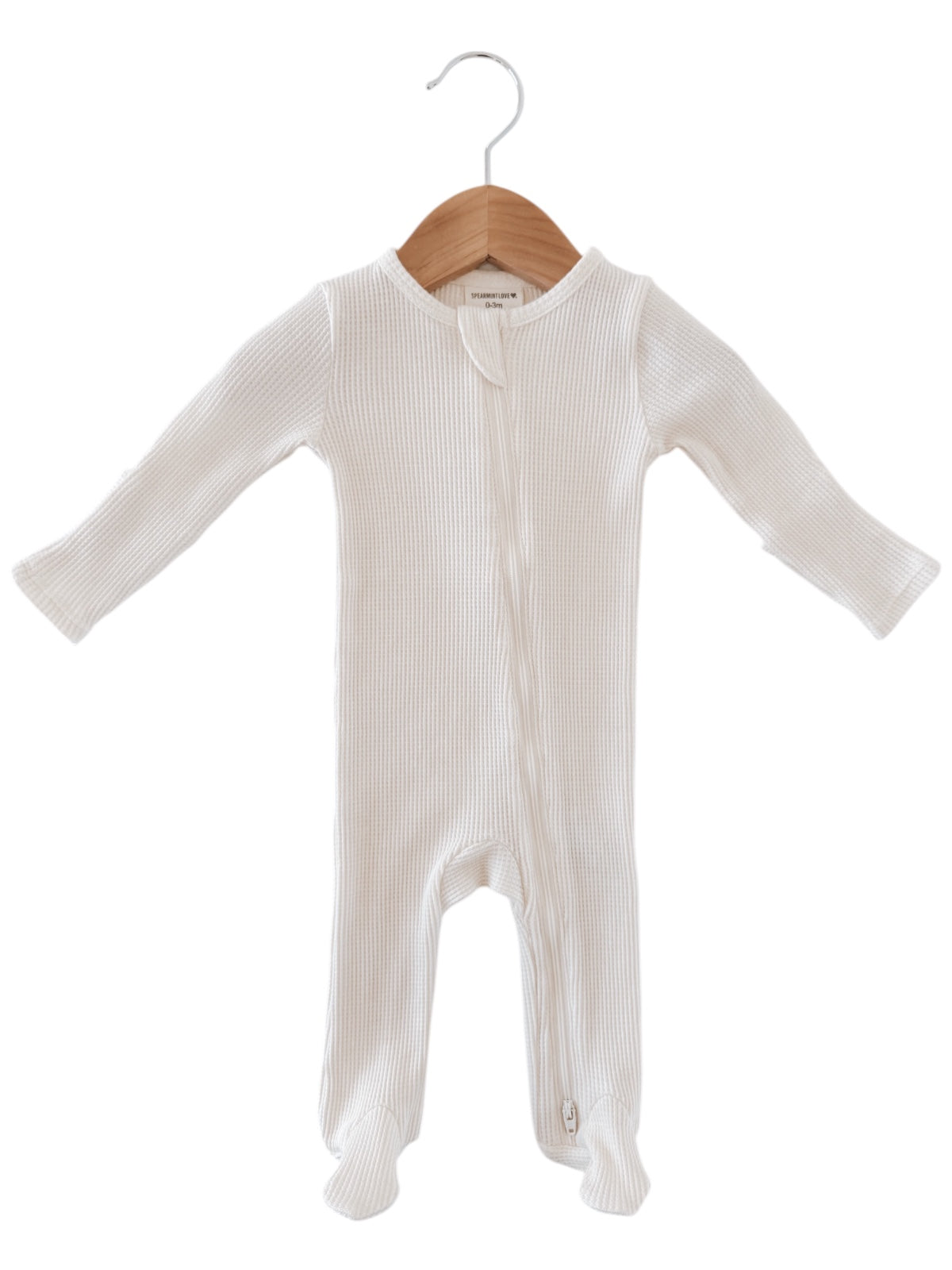 White baby onesie hanging on a wooden hanger, featuring a zipper and ribbed texture.