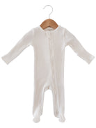 White baby onesie hanging on a wooden hanger, featuring a zipper and ribbed texture.