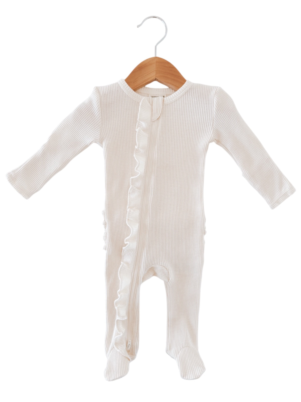 White baby onesie with ruffled side detail, hanging on a wooden hanger against a white background.