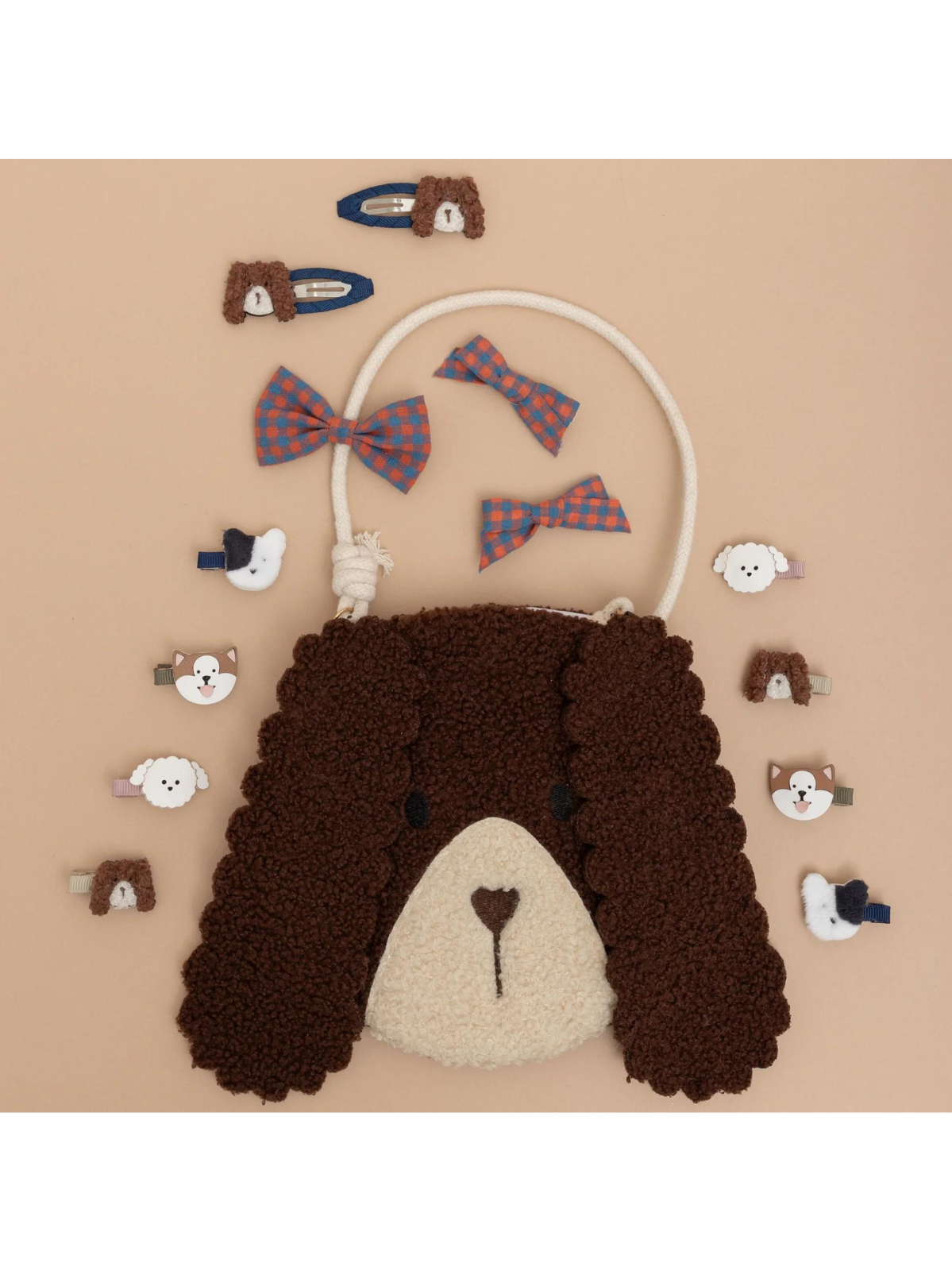 Brown dog-shaped bag surrounded by various hair clips and bows on a light background.