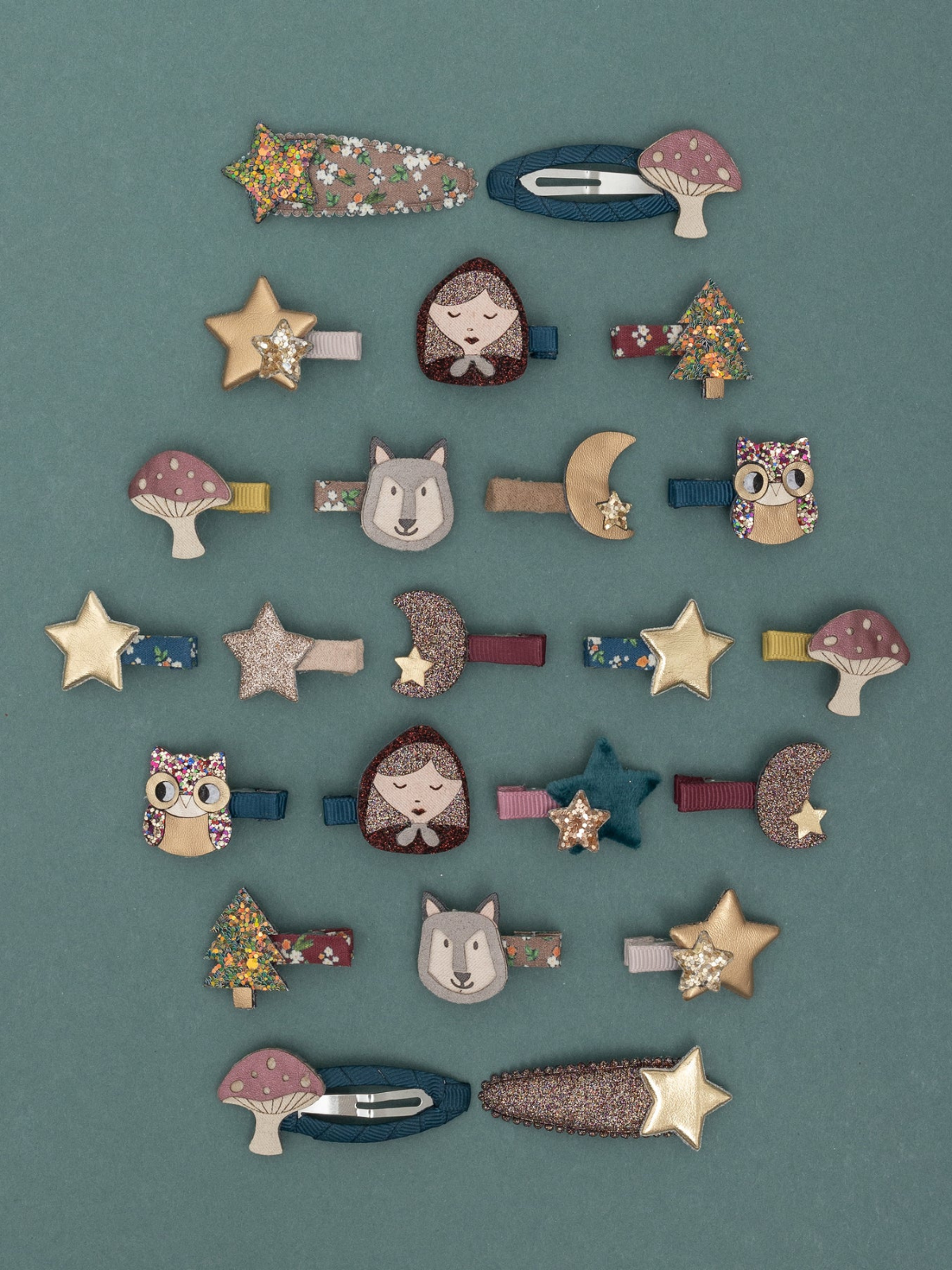 Colorful hair clips featuring animals, stars, mushrooms, and holiday themes on a teal background.