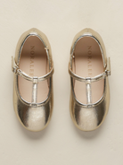 Gold metallic ballet shoes with a strap, top view on a light background.