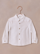 White long-sleeve button-up shirt on a copper hanger against a neutral background.