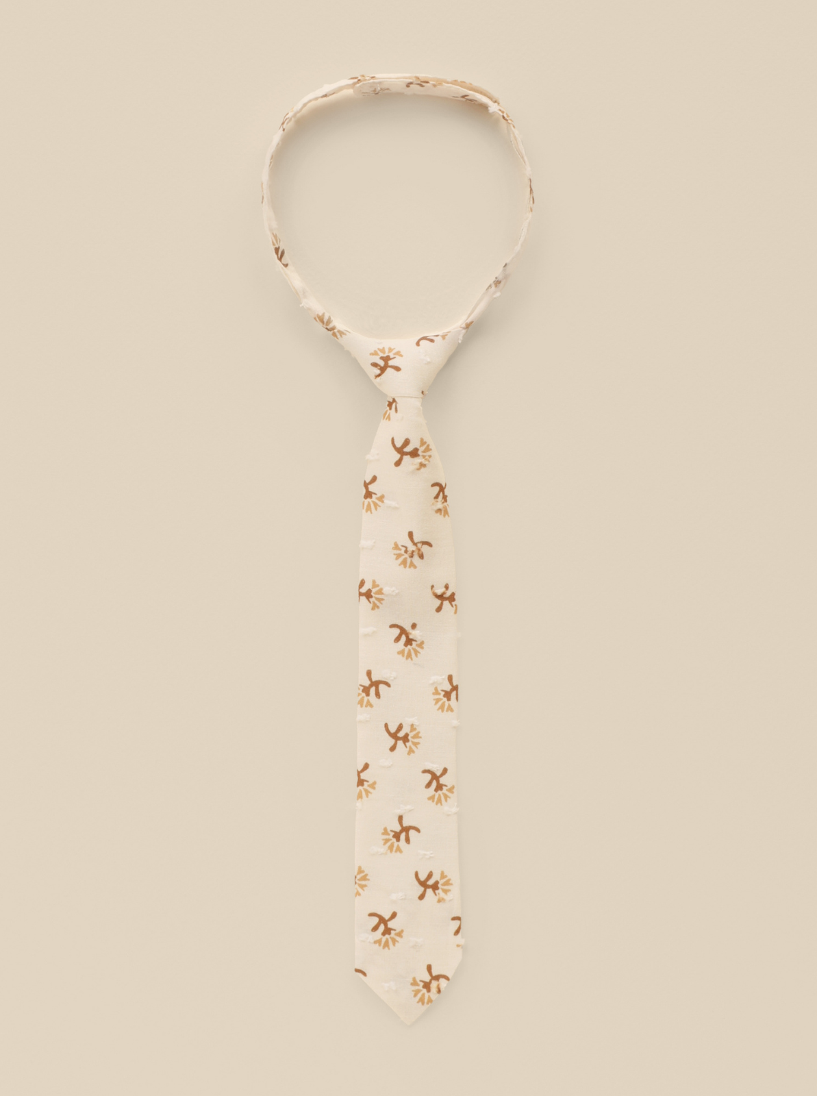 Beige tie with floral patterns on a light background, elegantly displayed for a stylish look.