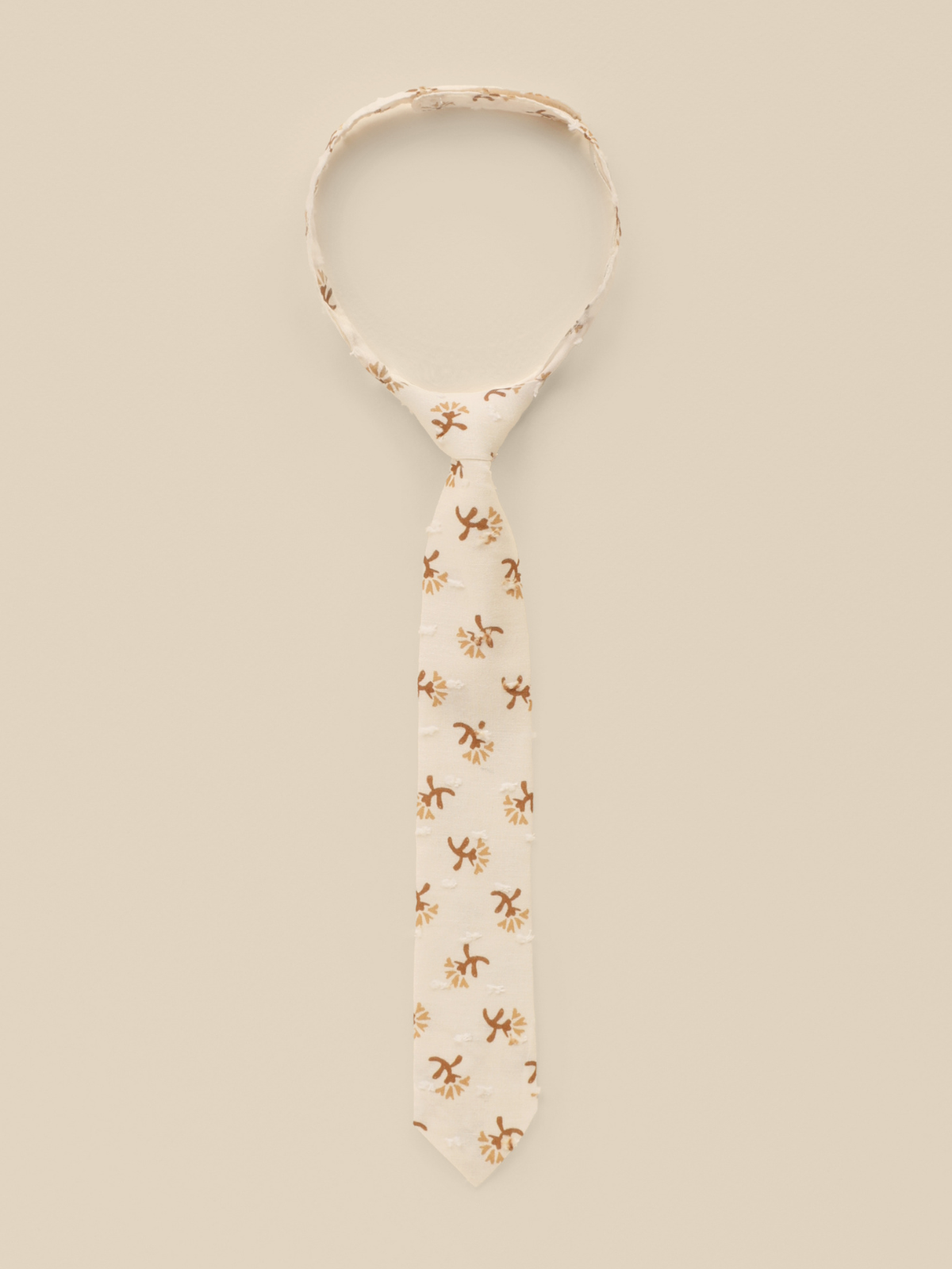 Beige tie with floral patterns on a light background, elegantly displayed for a stylish look.