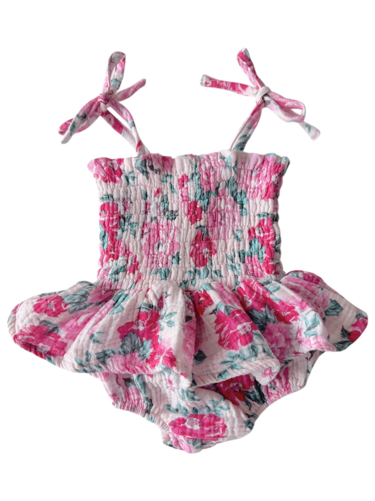 Pink floral romper with smocked bodice and ruffled skirt, featuring ties at the shoulders. Ideal for summer wear.
