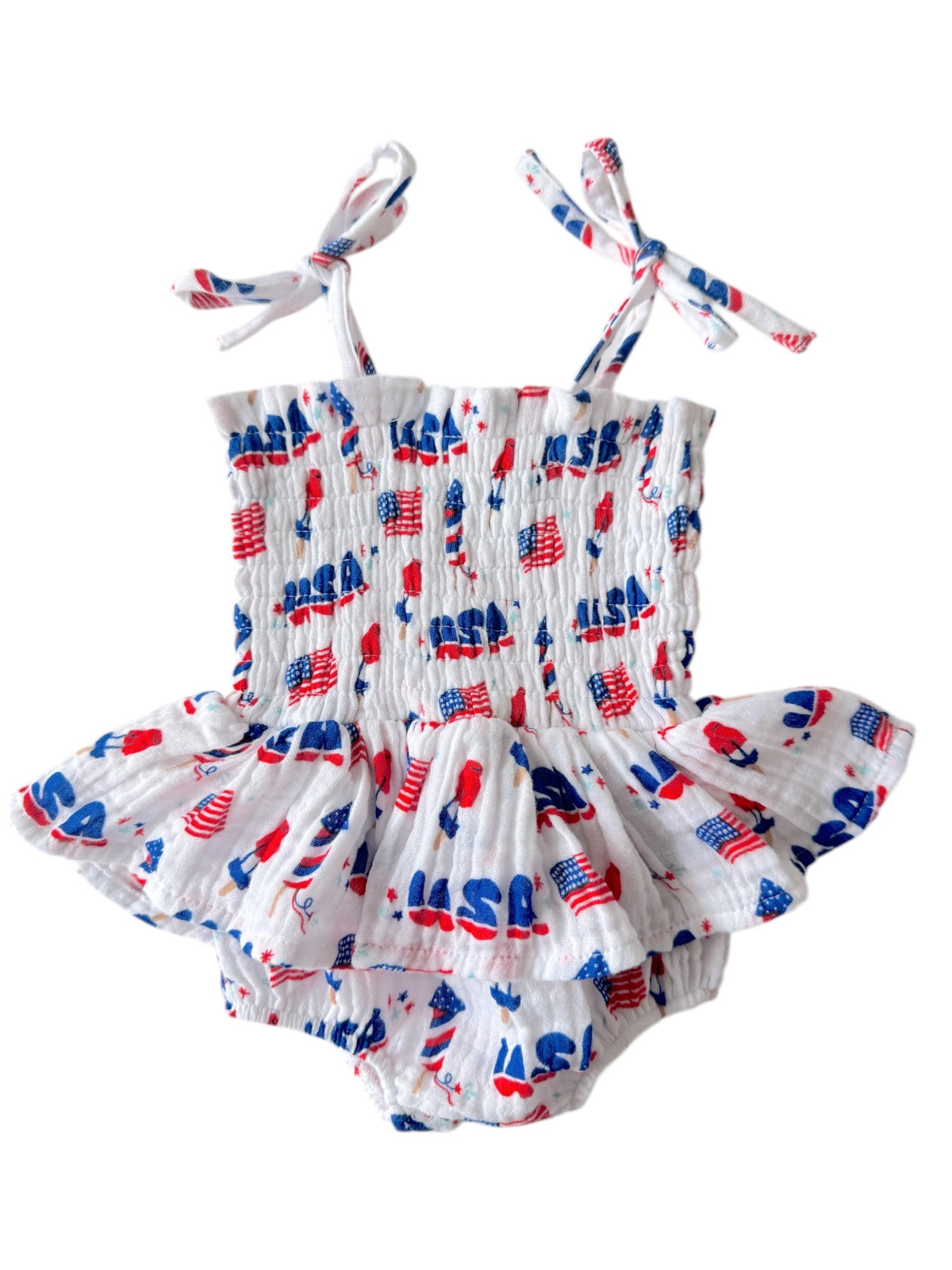 White baby romper with red and blue patriotic designs, featuring adjustable ties and a ruffled skirt.