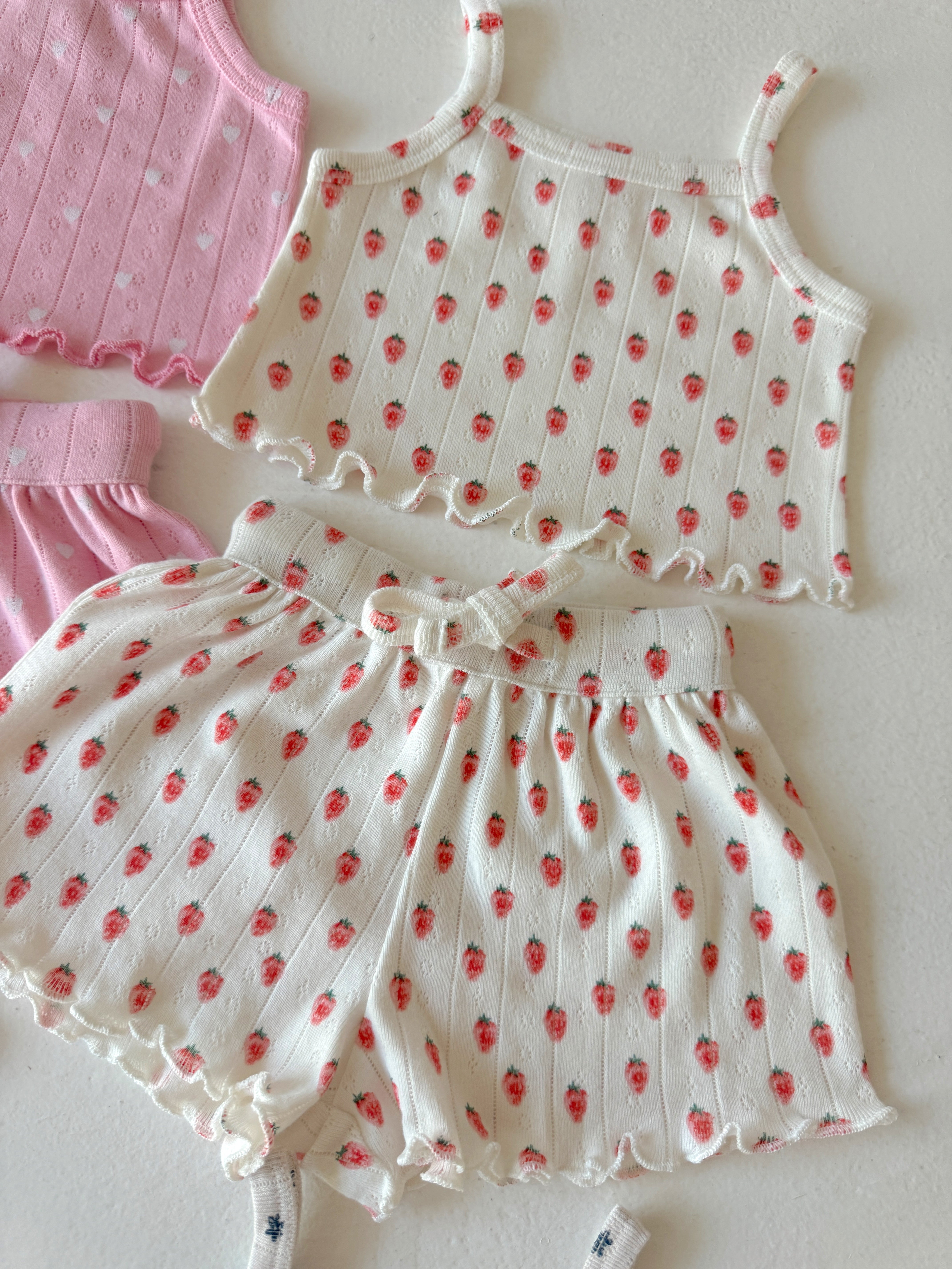 Pink and white floral-patterned kids' clothing set with a tank top and shorts on a light background.