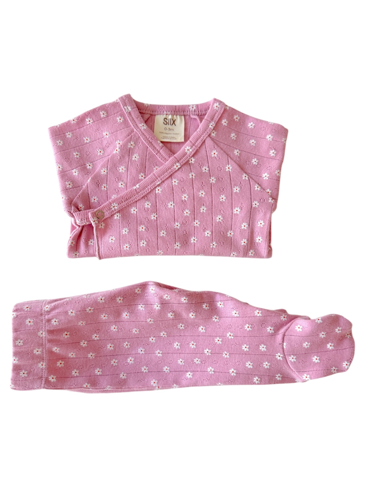 Pink infant outfit with short-sleeve top and long pants, featuring small white flower patterns. Size 0-3 months.