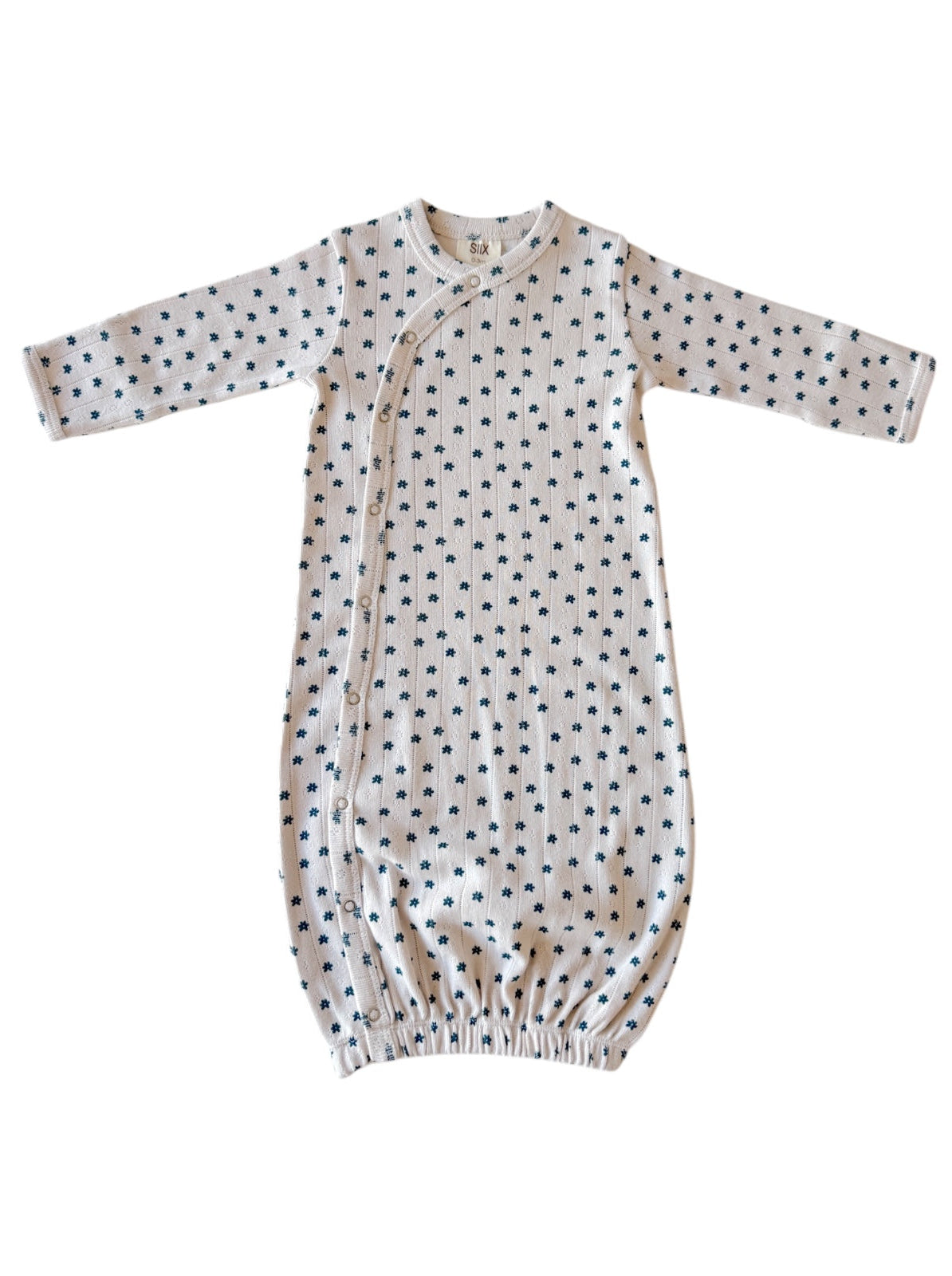 Light-colored baby gown with long sleeves and small navy floral print, featuring snap closures along the side.