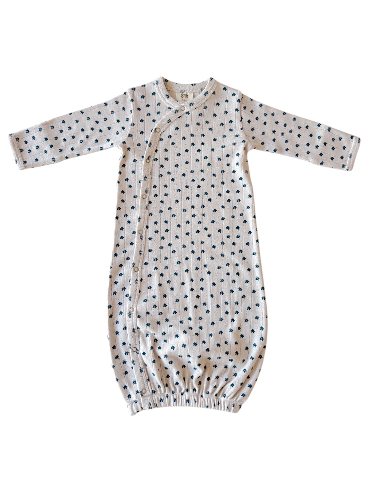Light-colored baby gown with long sleeves and small navy floral print, featuring snap closures along the side.