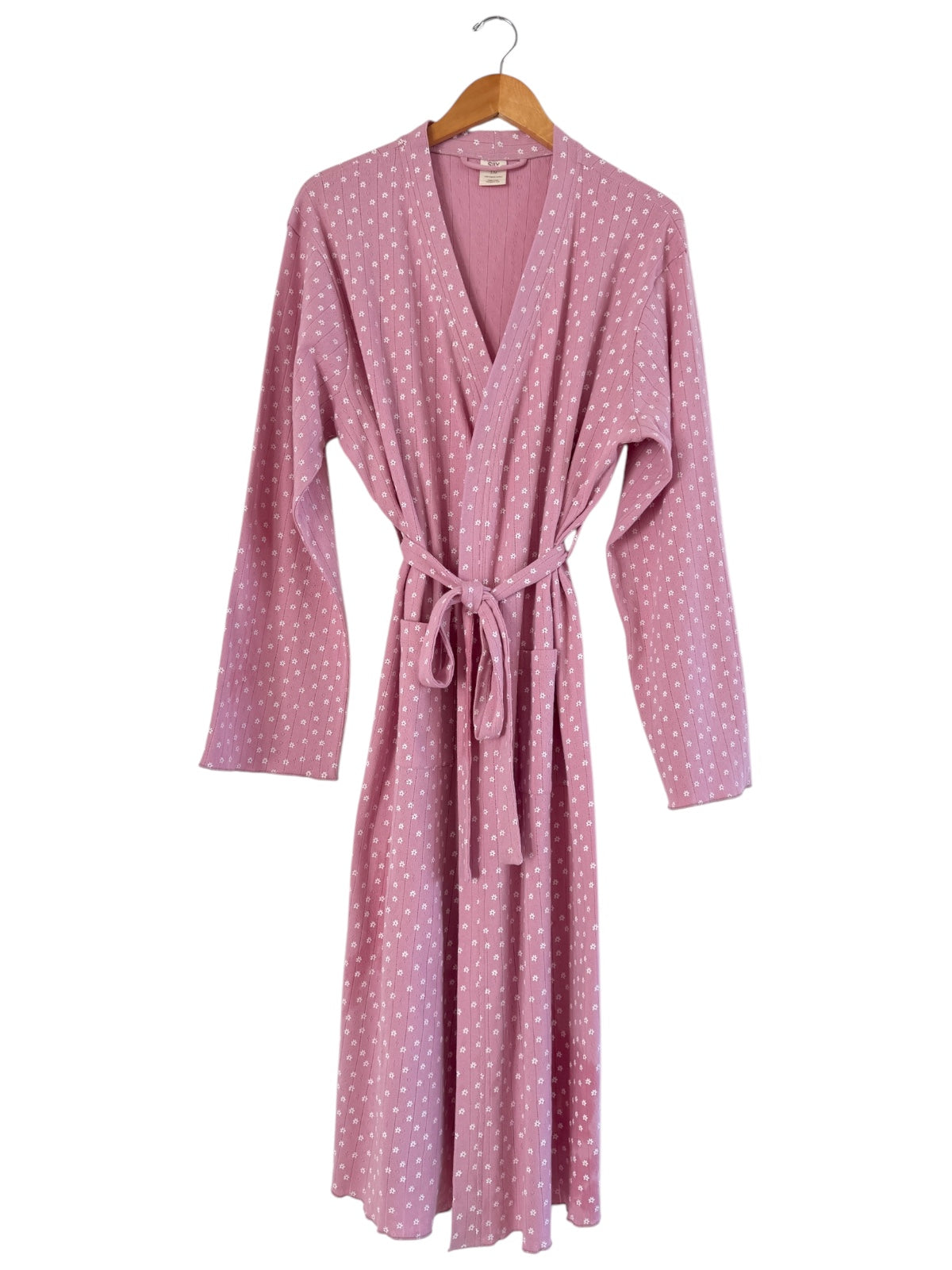 Pink robe with white polka dots, featuring a tie waist and long sleeves, displayed on a wooden hanger.