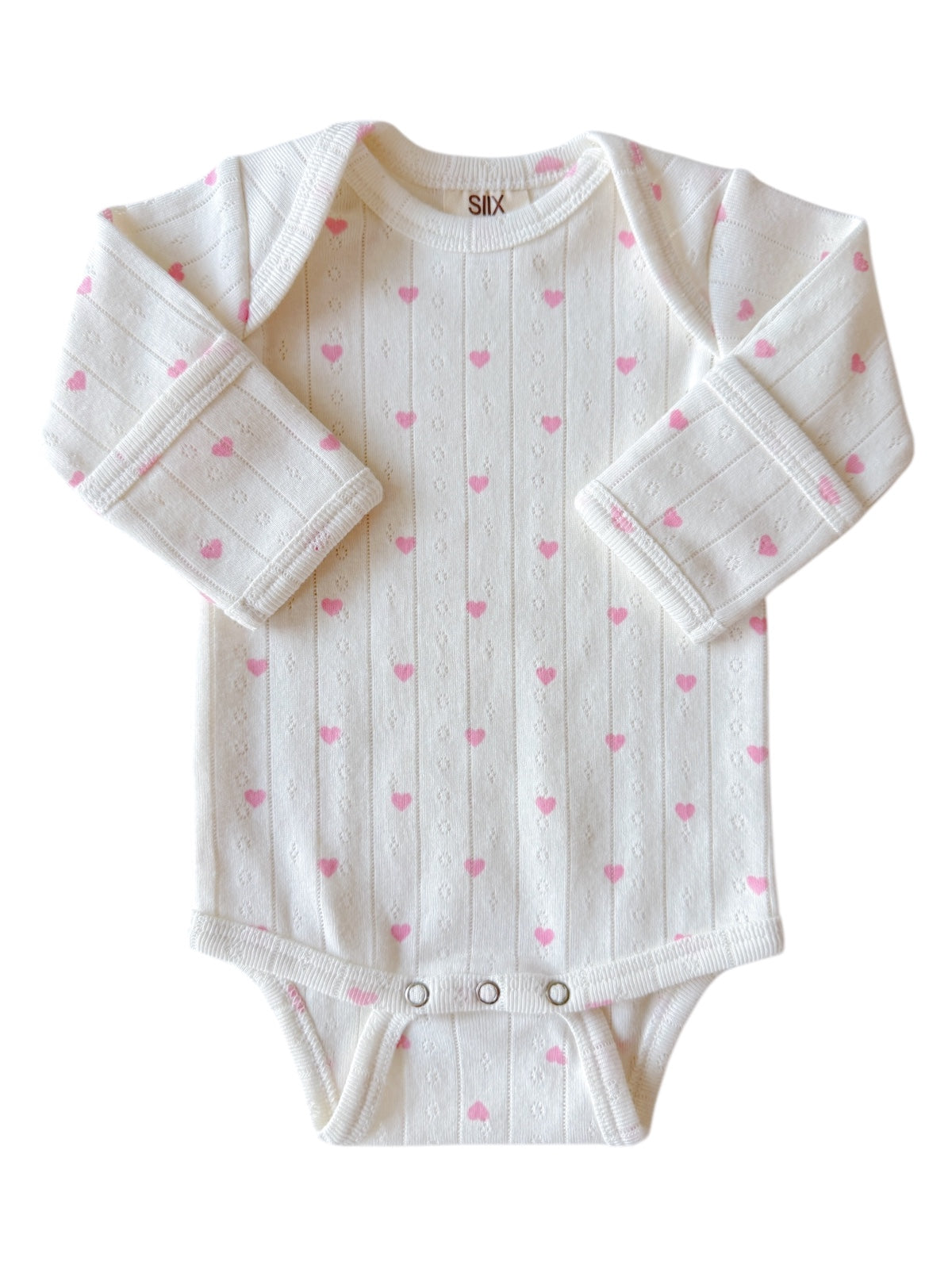 White baby onesie with pink heart patterns and long sleeves, featuring snap closures at the bottom.