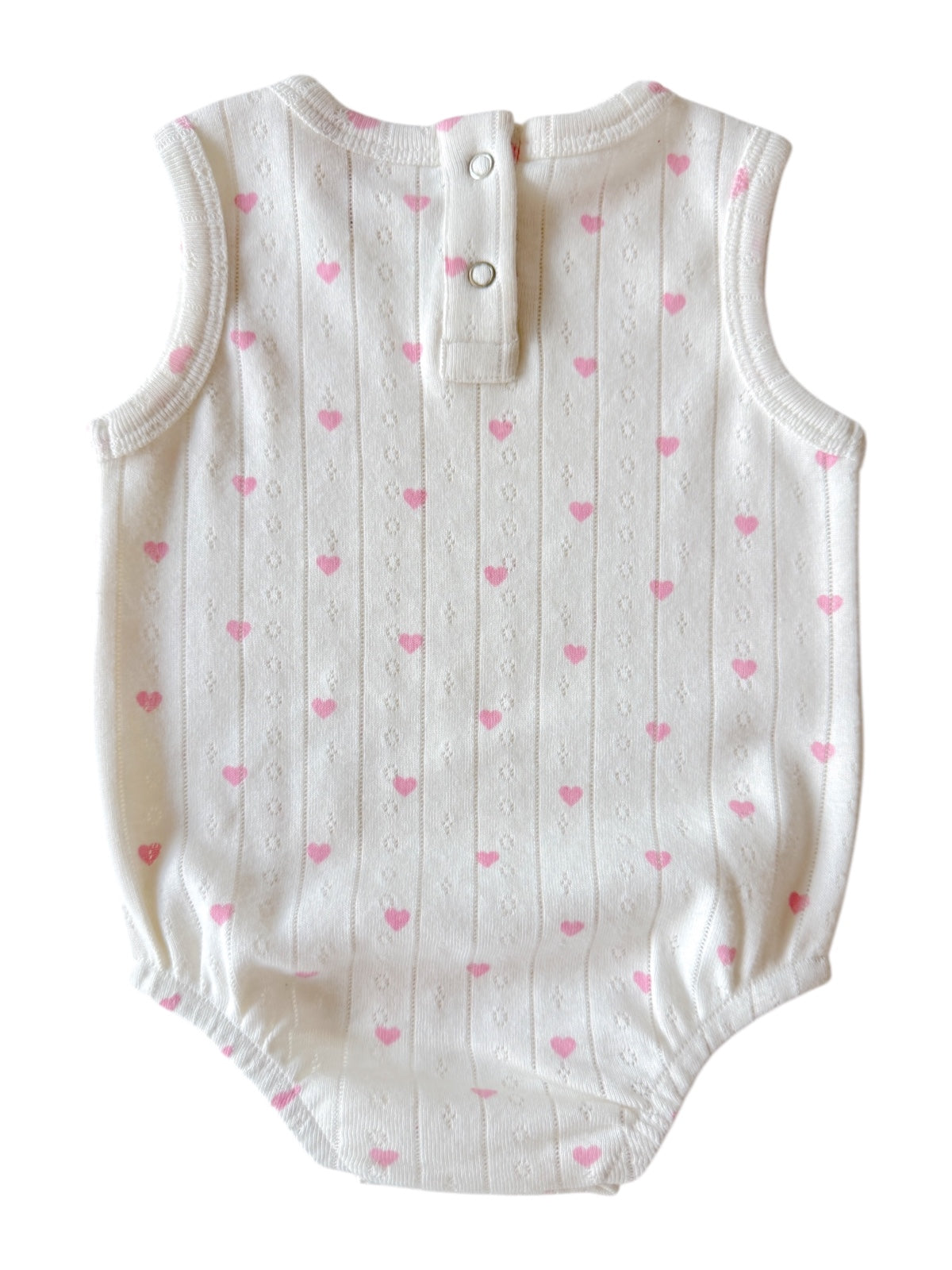 White baby onesie with pink heart pattern and buttons at the back. Perfect for casual infant wear.