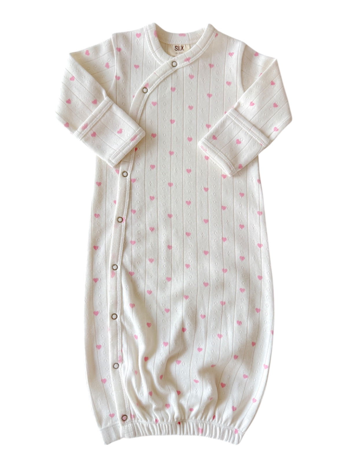 White infant sleep sack with pink heart patterns and button closures, designed for comfort and easy dressing.