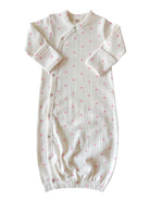 White infant sleep sack with pink heart patterns and button closures, designed for comfort and easy dressing.