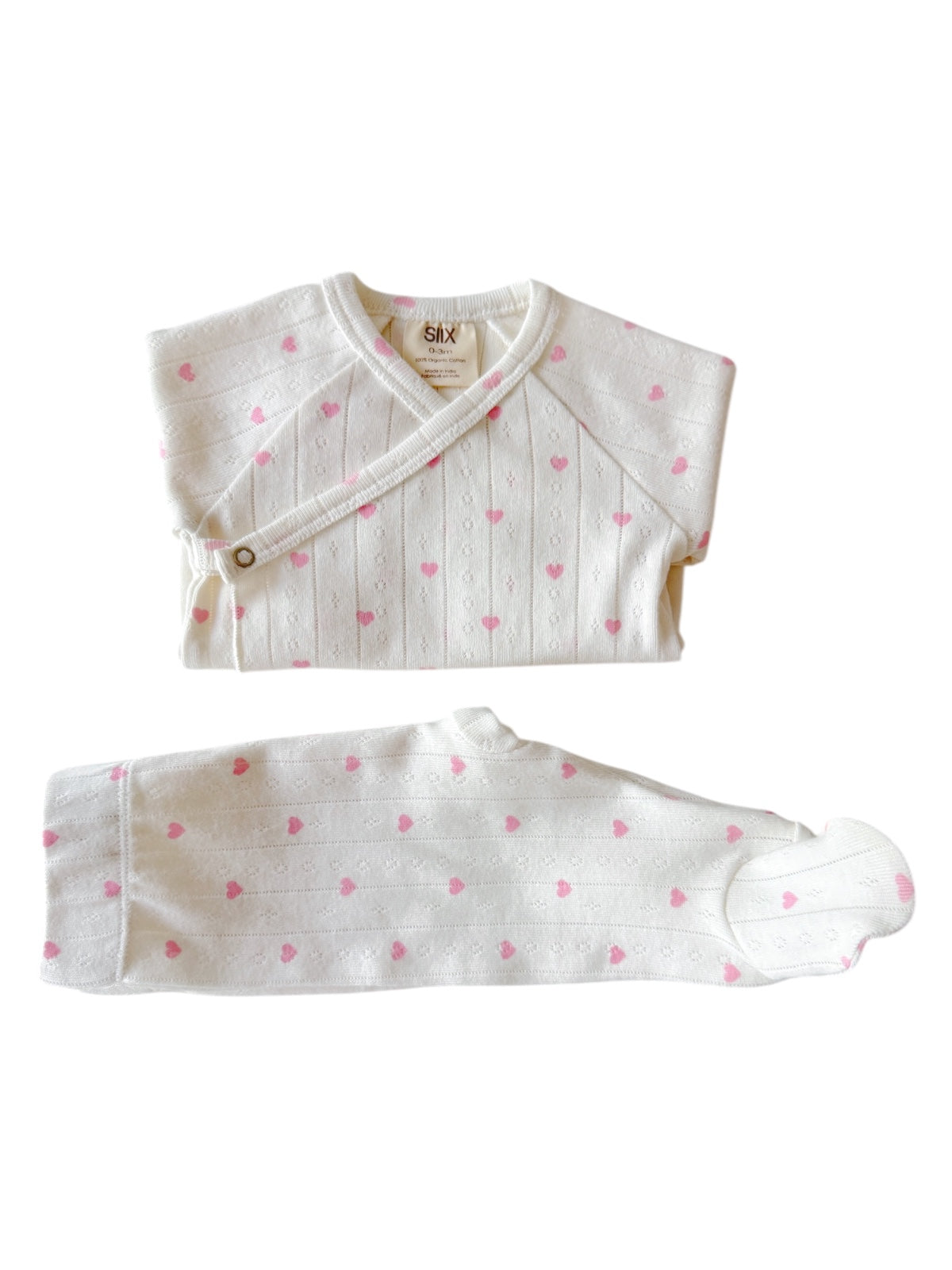 White baby outfit featuring a wrap top with pink hearts and matching pants, soft and cozy for infants.