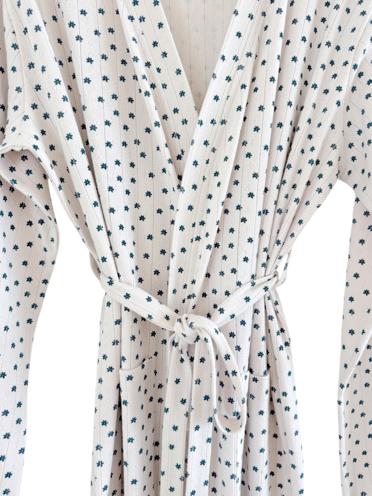 Wrap dress featuring small floral patterns in blue on a white background, tied at the waist with pockets.