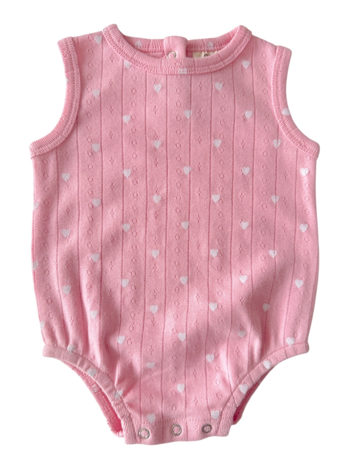 Pink sleeveless baby onesie with white heart patterns and snap closures at the bottom.