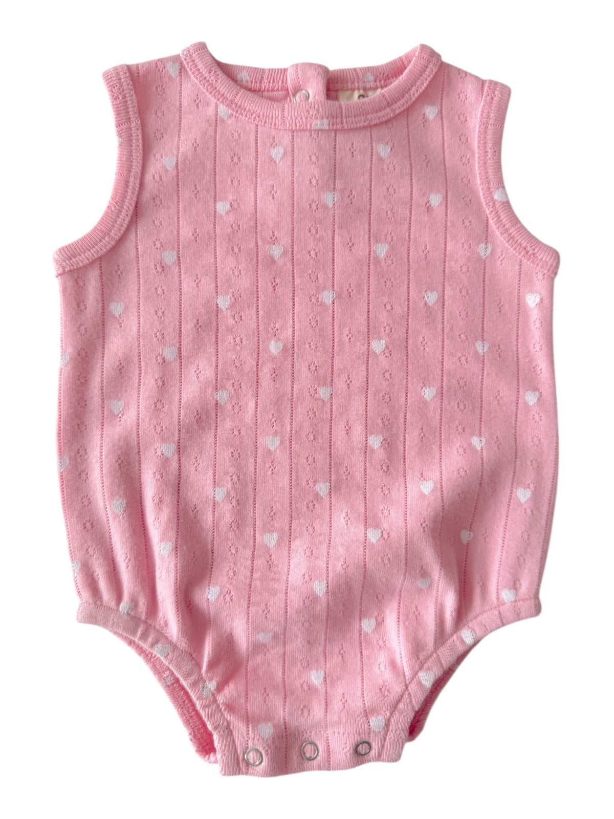 Pink sleeveless baby onesie with white heart patterns and snap closures at the bottom.