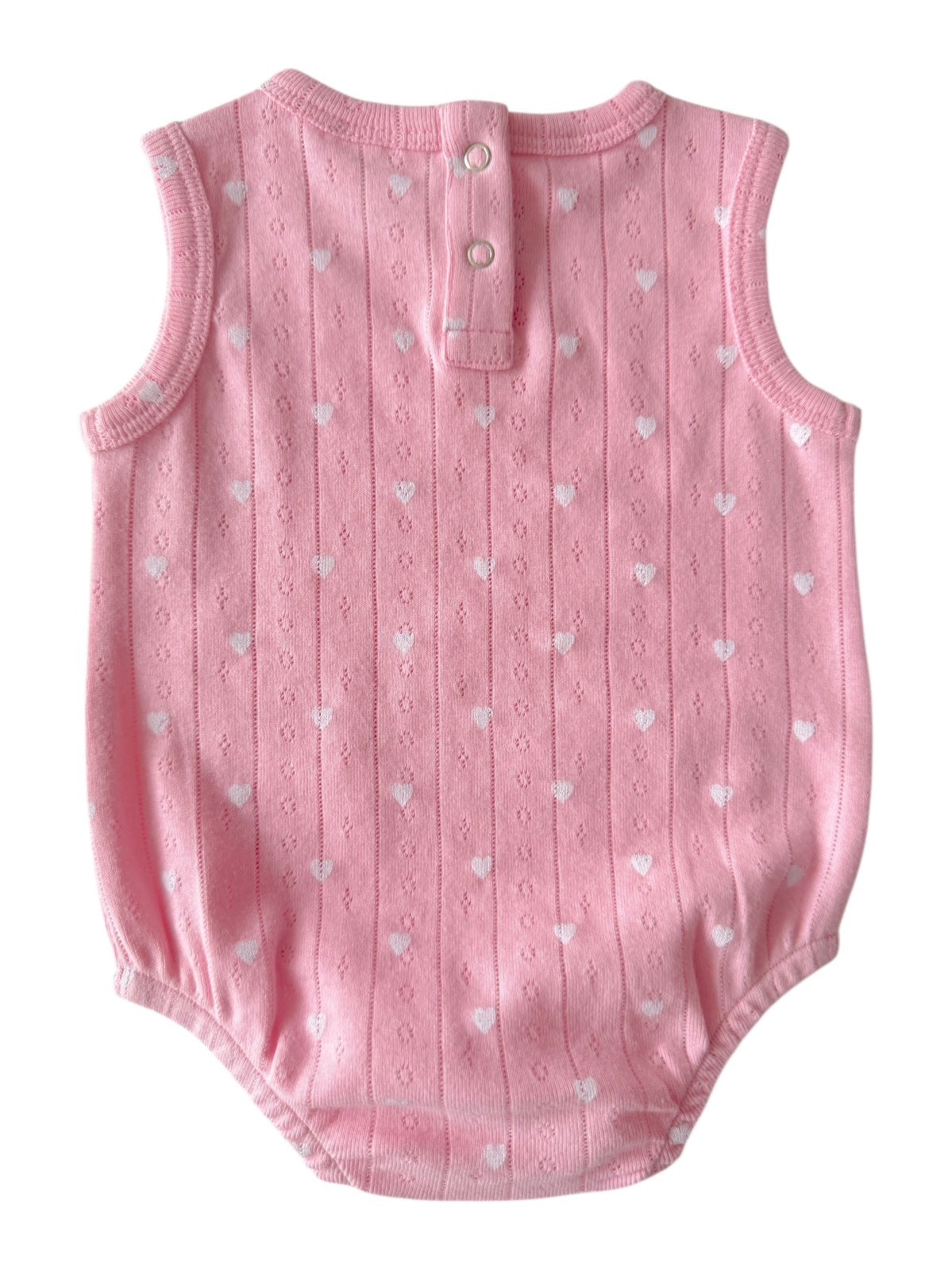 Pink sleeveless baby romper with white heart patterns and button closure at the back.