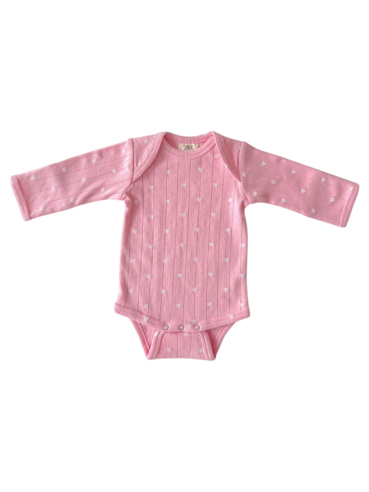 Light pink baby onesie with white polka dots and long sleeves, featuring button closures at the bottom.