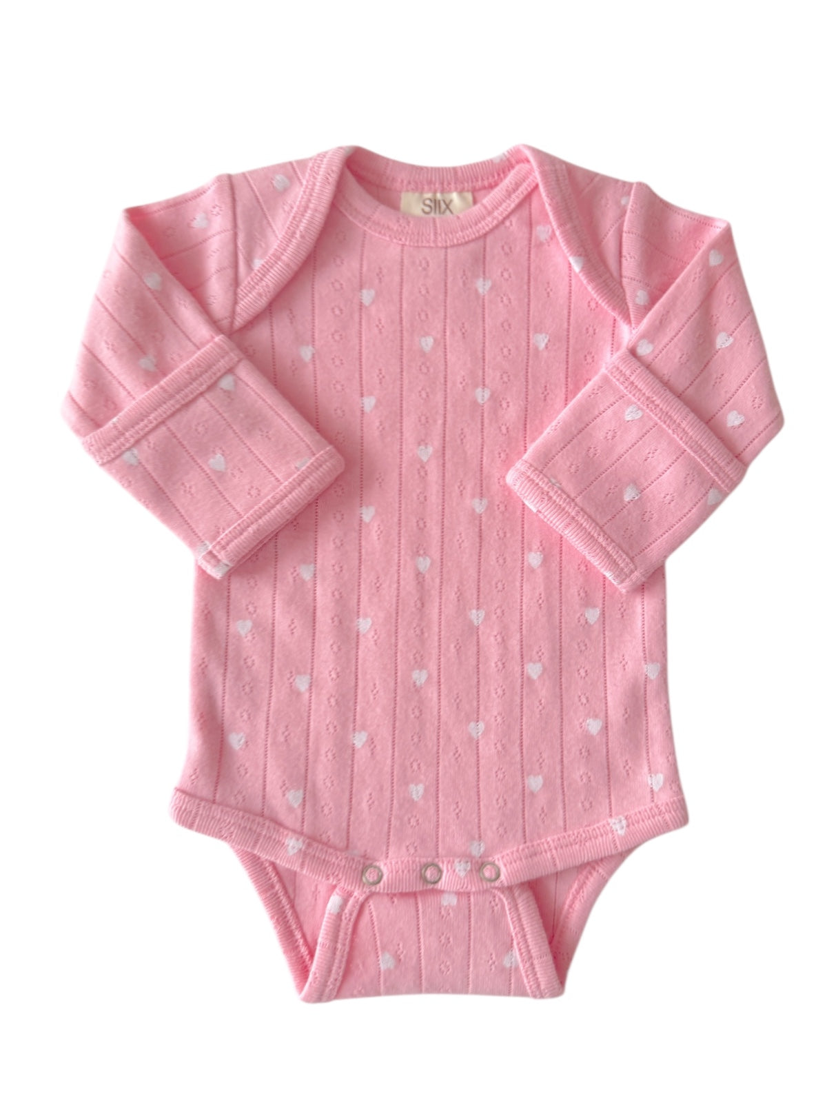Pink baby onesie with white heart patterns and long sleeves, featuring snap closures at the bottom.
