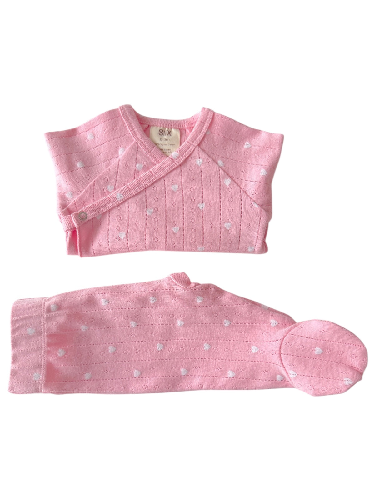 Pink baby outfit with hearts, including a wrap top, pants, and a matching hat. Soft and cozy for infants.