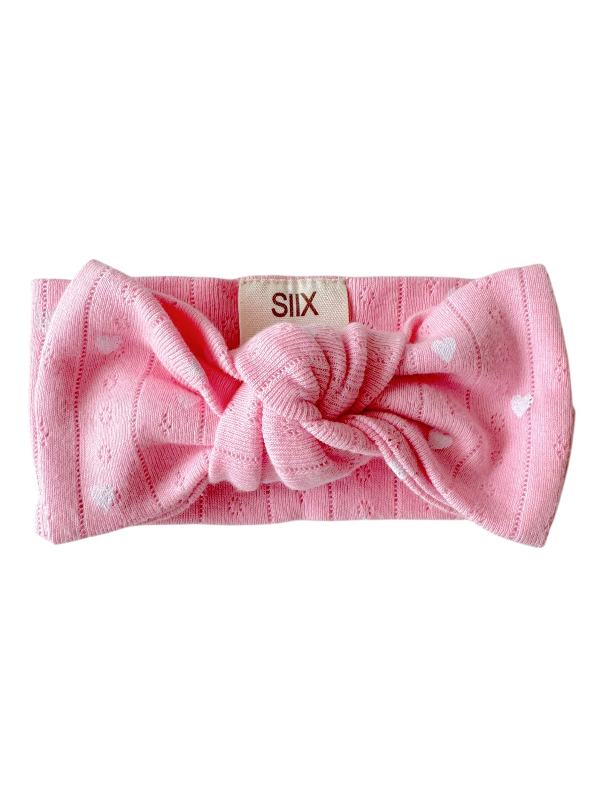 Pink headband with a knot and heart patterns, labeled with "SIIX." Ideal for stylish and comfortable wear.