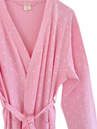Pink robe with white heart patterns, featuring a tie belt and long sleeves.