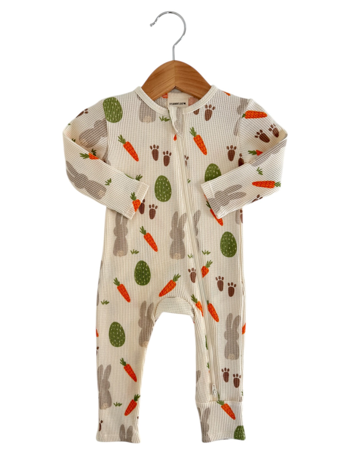Infant onesie featuring playful bunny and carrot patterns, hanging on a wooden hanger against a white background.