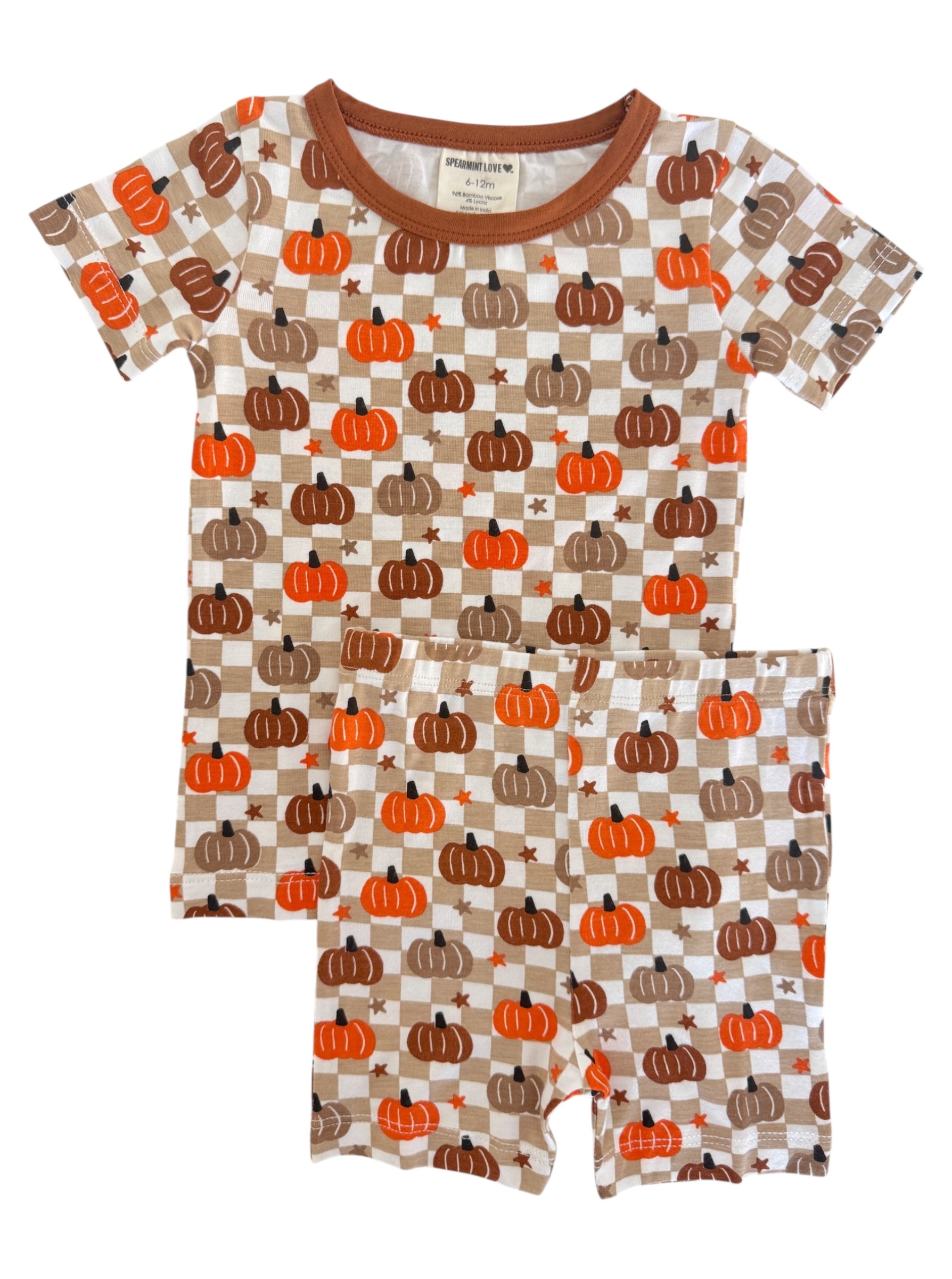 Children's pajama set featuring a pumpkin and checkerboard pattern in orange, brown, and cream colors.