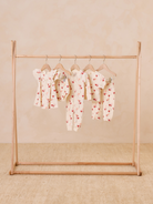 Children's clothing with heart patterns displayed on a wooden rack against a neutral background.