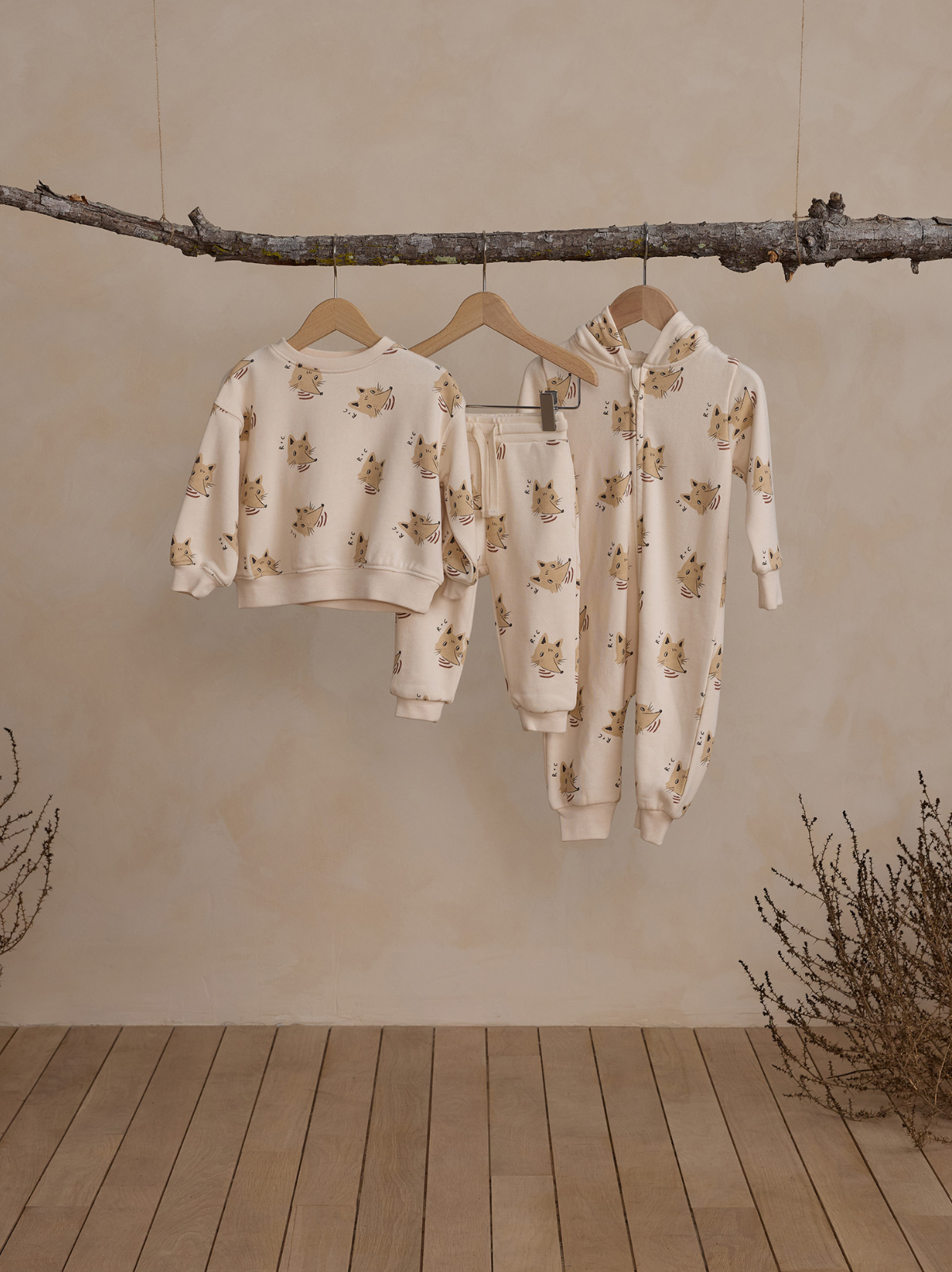 Children's clothing displayed on hangers; cream fabric with playful animal patterns against a neutral backdrop.
